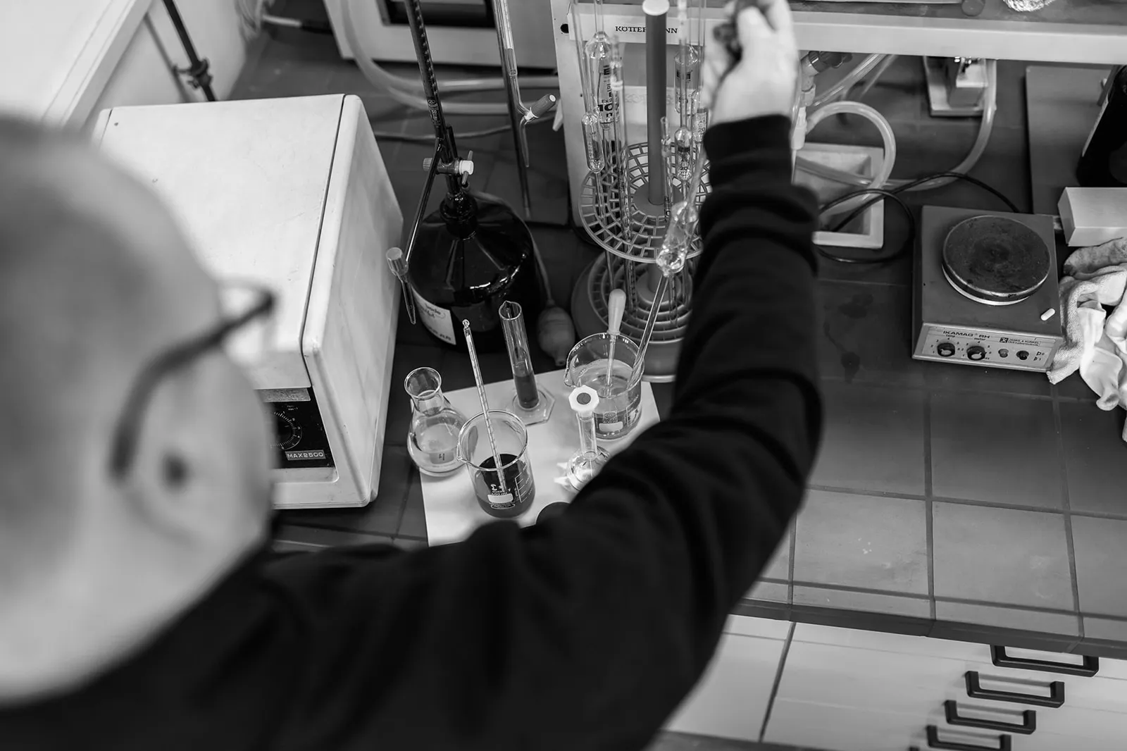 Blick über die Schulter auf Glasgeräte und Messzylinder im Labor