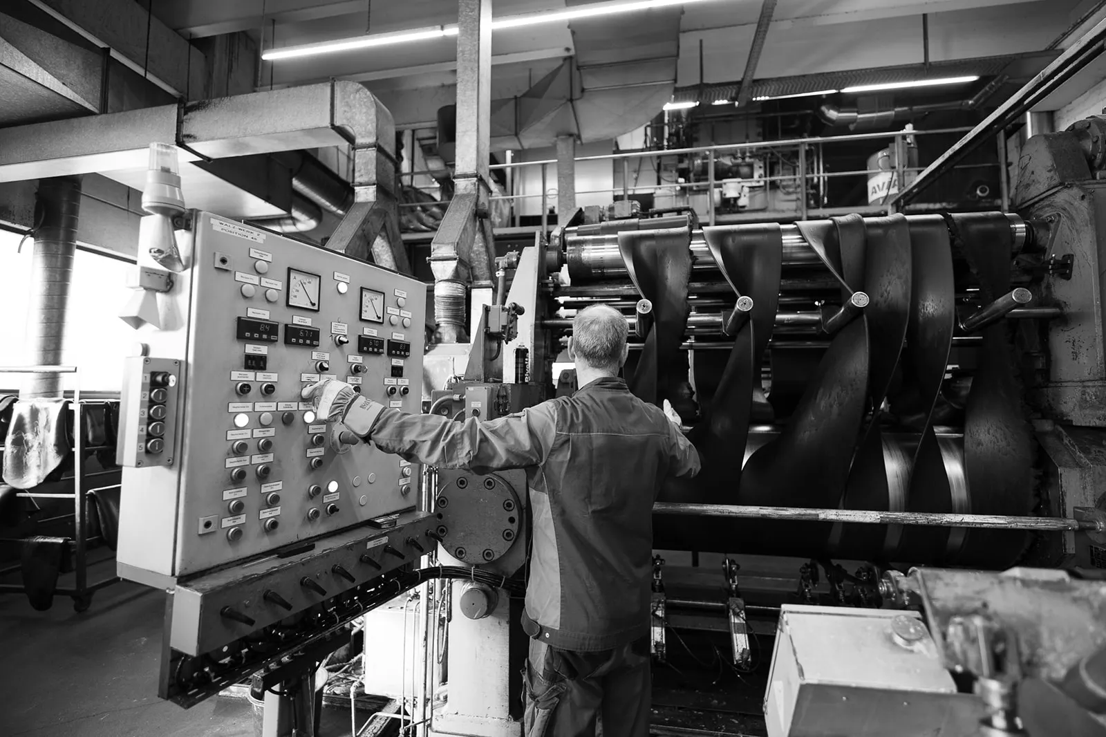 Mitarbeiter bedient das Schaltpult eines Walzwerks in der Produktion